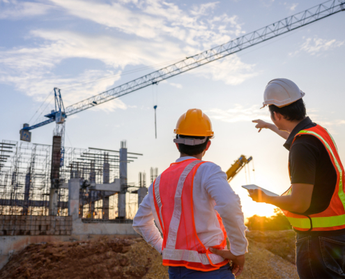 A team of construction engineers talks to managers and construction workers at the construction site